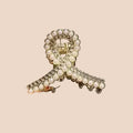 Hair clip with decorative elements held by a hand against a neutral background