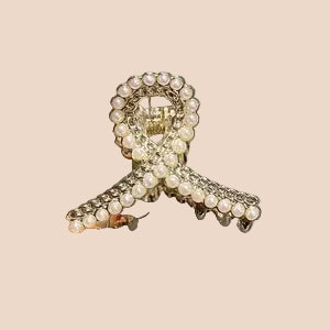 Hair clip with decorative elements held by a hand against a neutral background