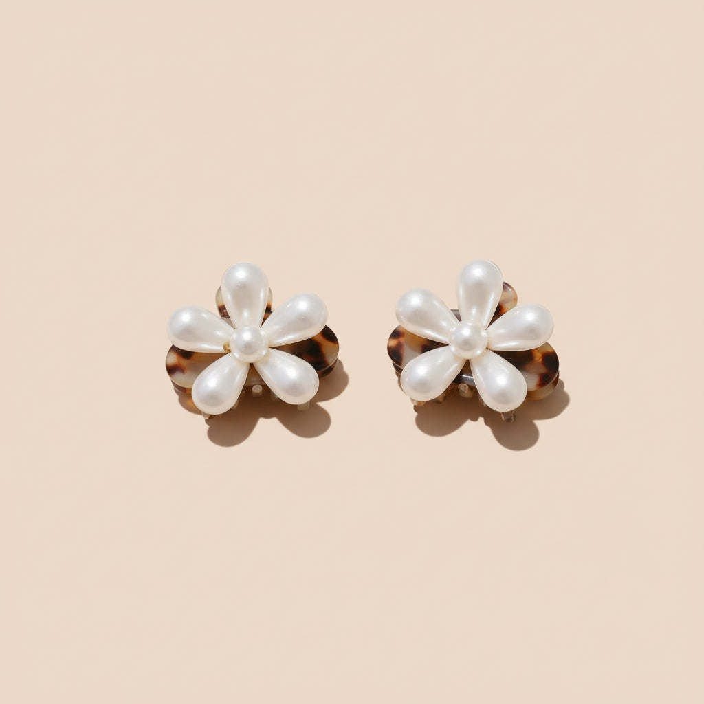 Pearl flower hair clip held by a hand against a neutral background